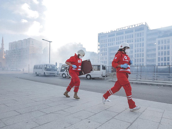 Två rödklädda personer springer med rök i bakgrunden